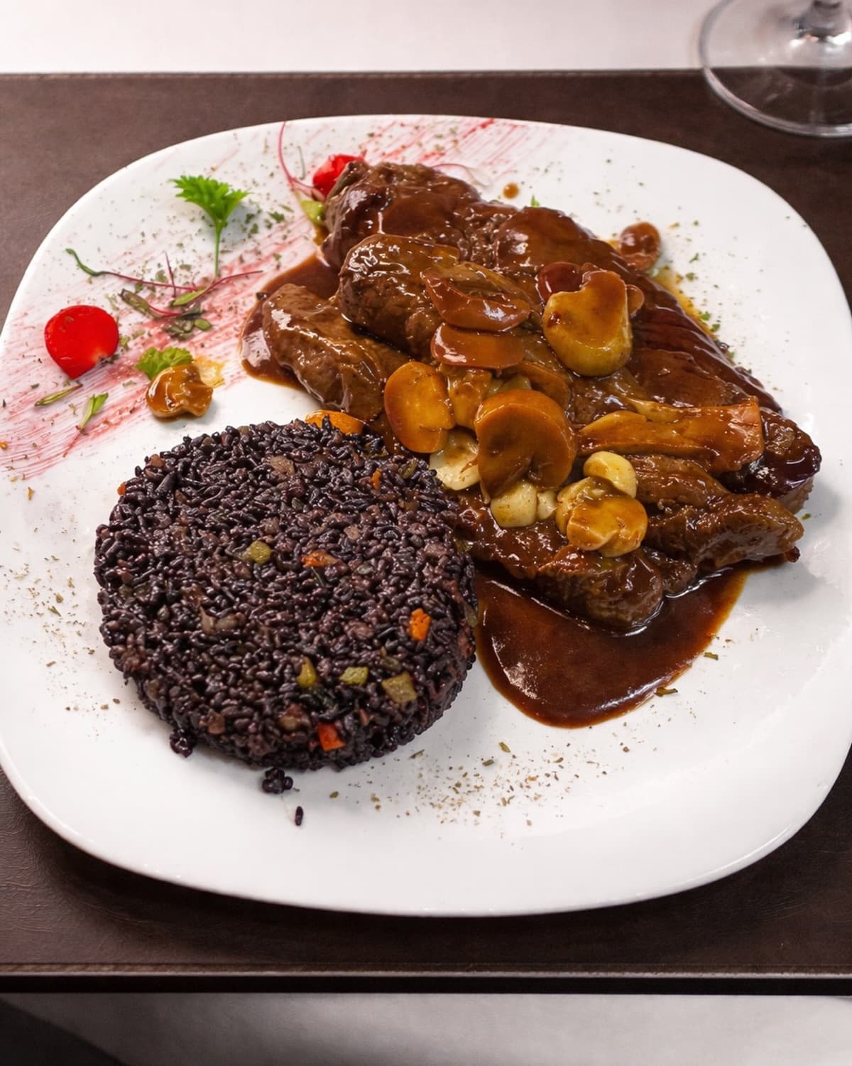 Uma das assinaturas da casa, servida com arroz negro e molho de vinho.